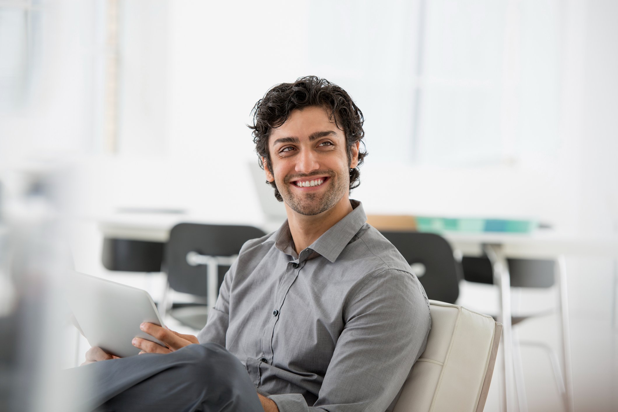 A-man-seated-smiling-and-holding-a-digital-tablet-quotes-to-motivate-a-team