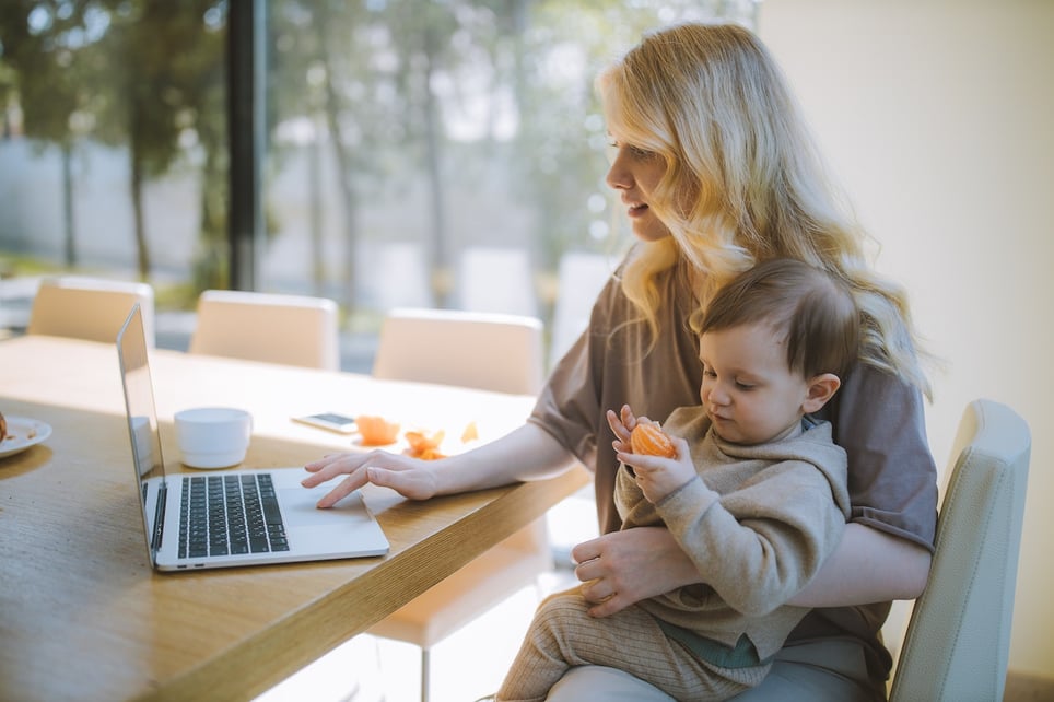 Babysitter-carrying-a-toddler-while-she-writes-on-her-laptop-at-home-how-to-put-babysitter-on-a-resume