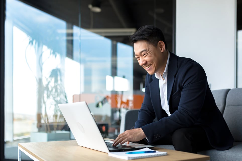 Business-man-smiling-and-proud-looking-at-laptop-how-to-end-an-email