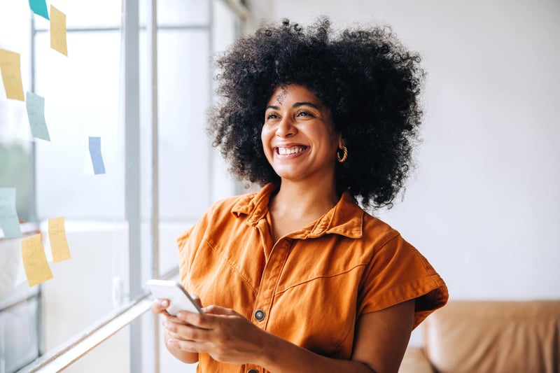 Confident-woman-standing-in-front-of-post-it-filled-window-examples-of-development-opportunities