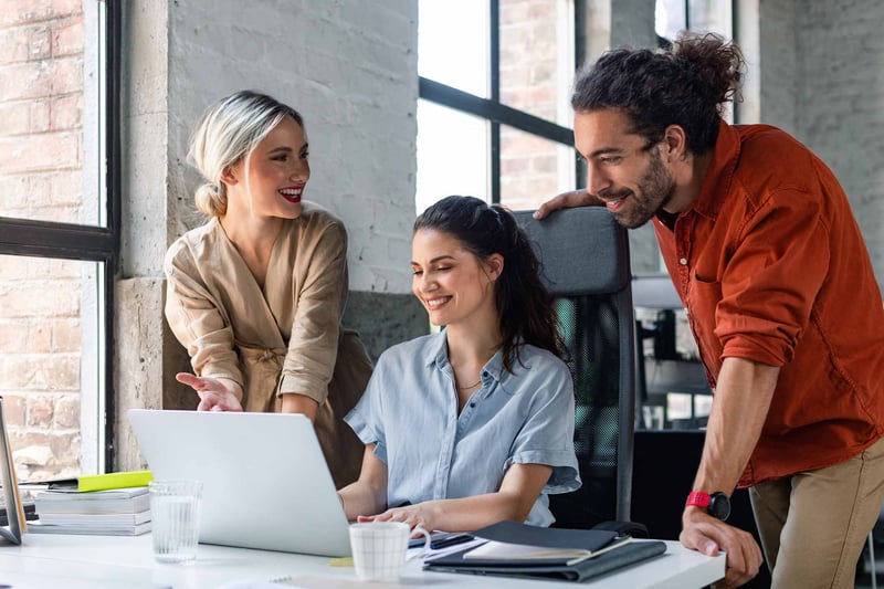 Coworkers-looking-at-laptop-and-smiling-at-office-employee-value-proposition