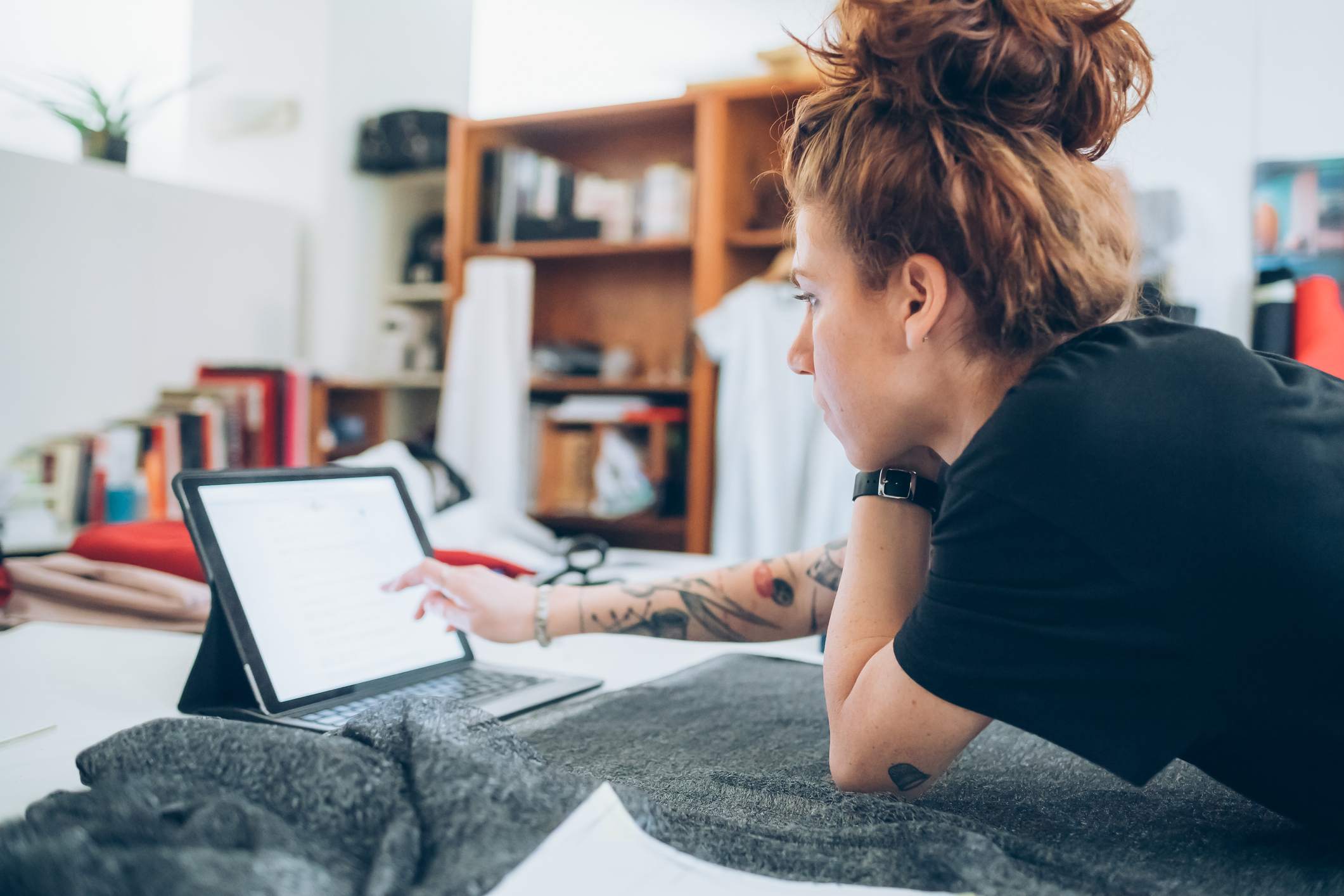 Creative-woman-with-tattoos-on-her-arm-looking-at-her-ipad-at-her-workshop-life-skills