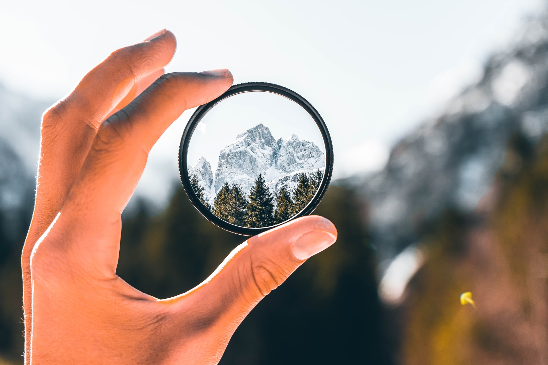 Cropped-hand-holding-a-camera-filter-with-view-of-mountain-factors-that-promote-resilience