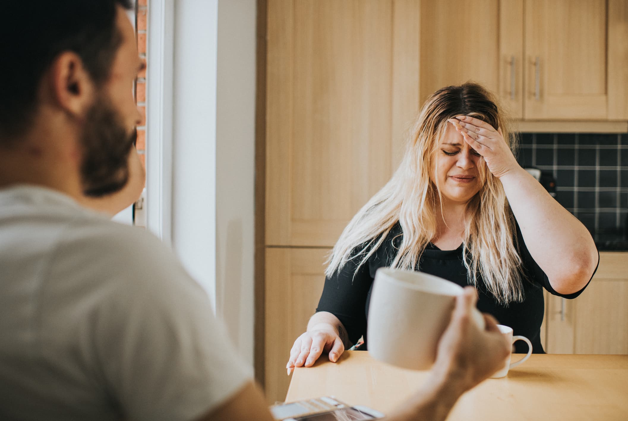 Distressed-woman-at-a-kitchen-table-talking-to-her-partner-green-flags-in-relationships