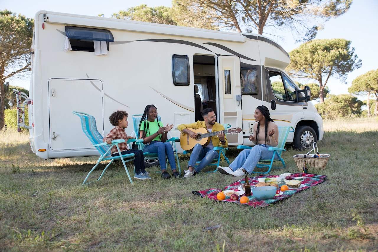 Family-with-kids-on-the-side-of-the-road-with-RV-playing-guitar-and-eating-quality-time-with-family