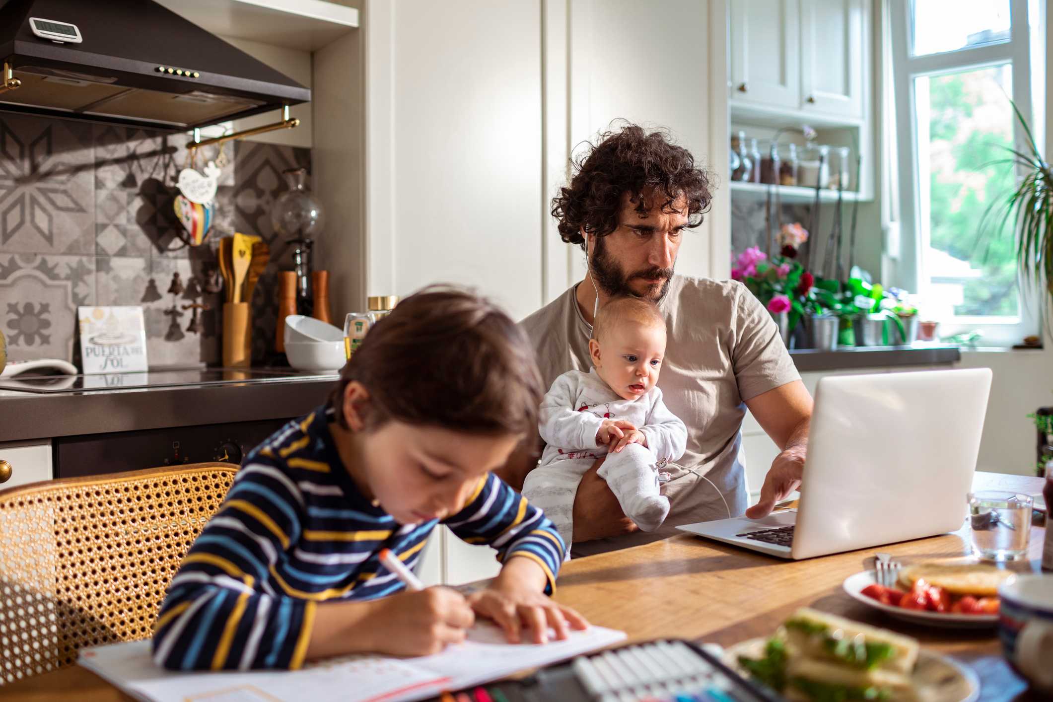 Father-at-home-writing-in-his-laptop-while-holding-baby-out-of-office-message