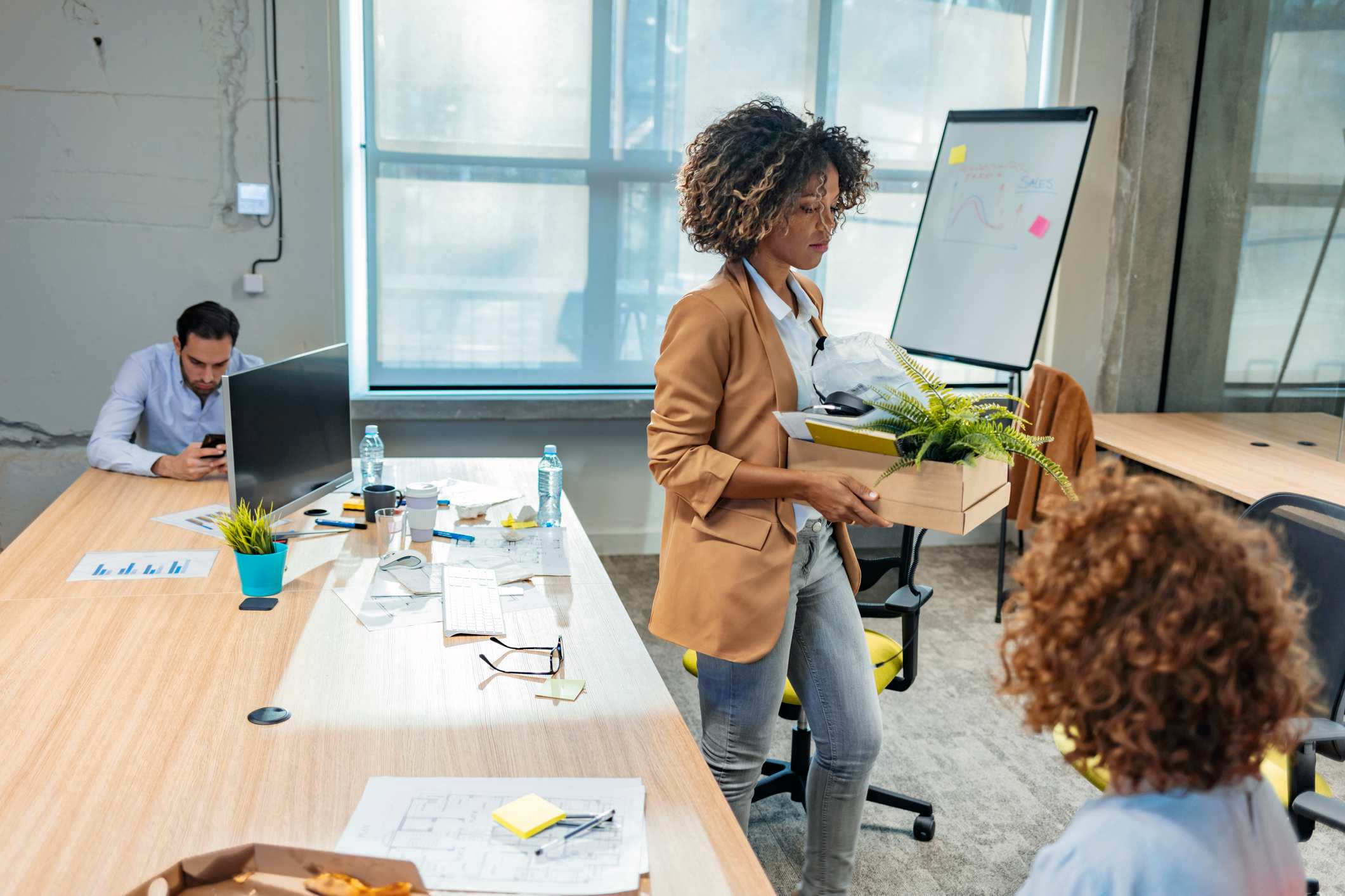 Fired-female-employee-holding-box-of-belongings-in-an-office-asking-for-a-raise-tips