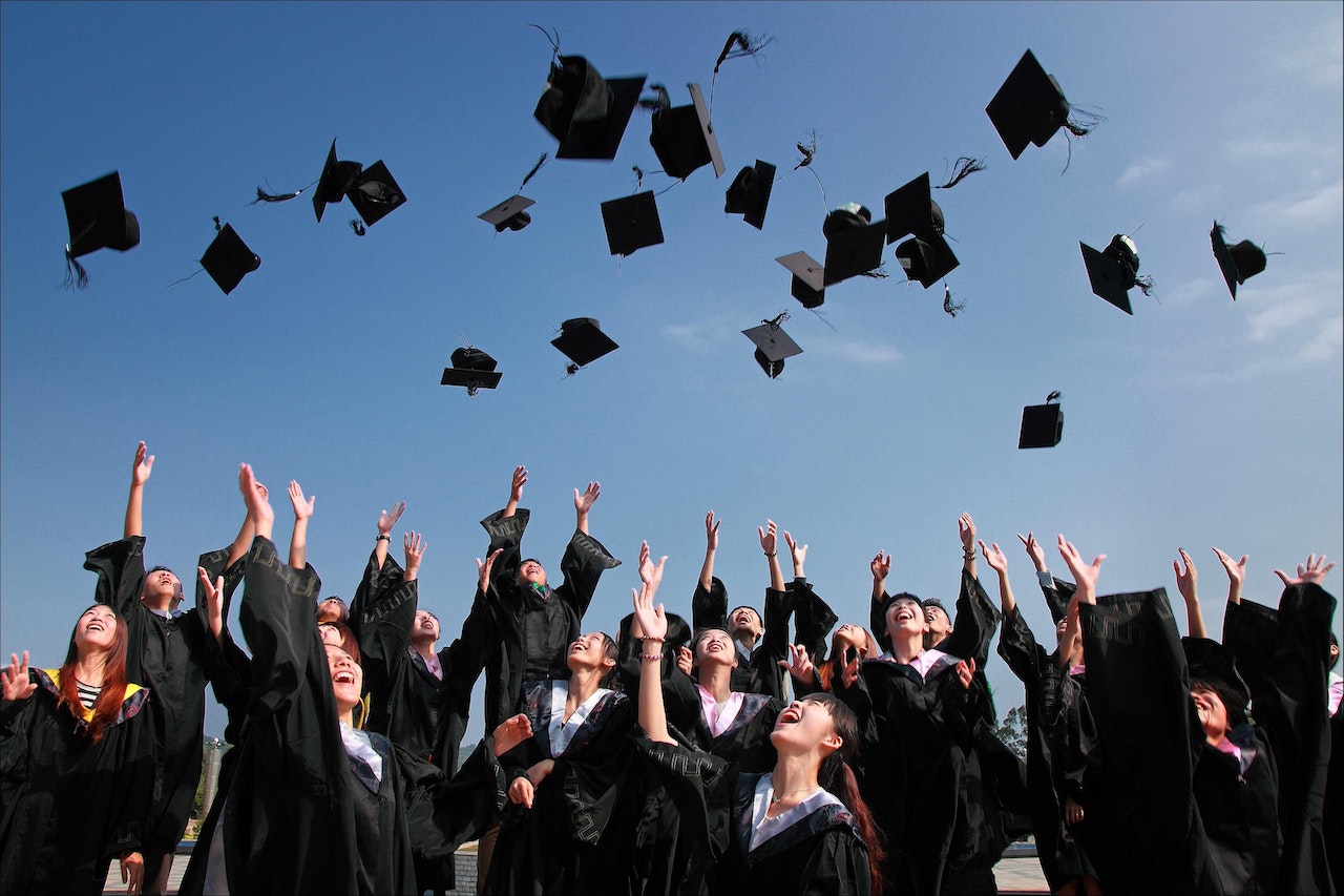 Graduating-class-throwing-caps-in-the-air-at-college-ceremony-magna-cum-laude-vs-summa-cum-laude