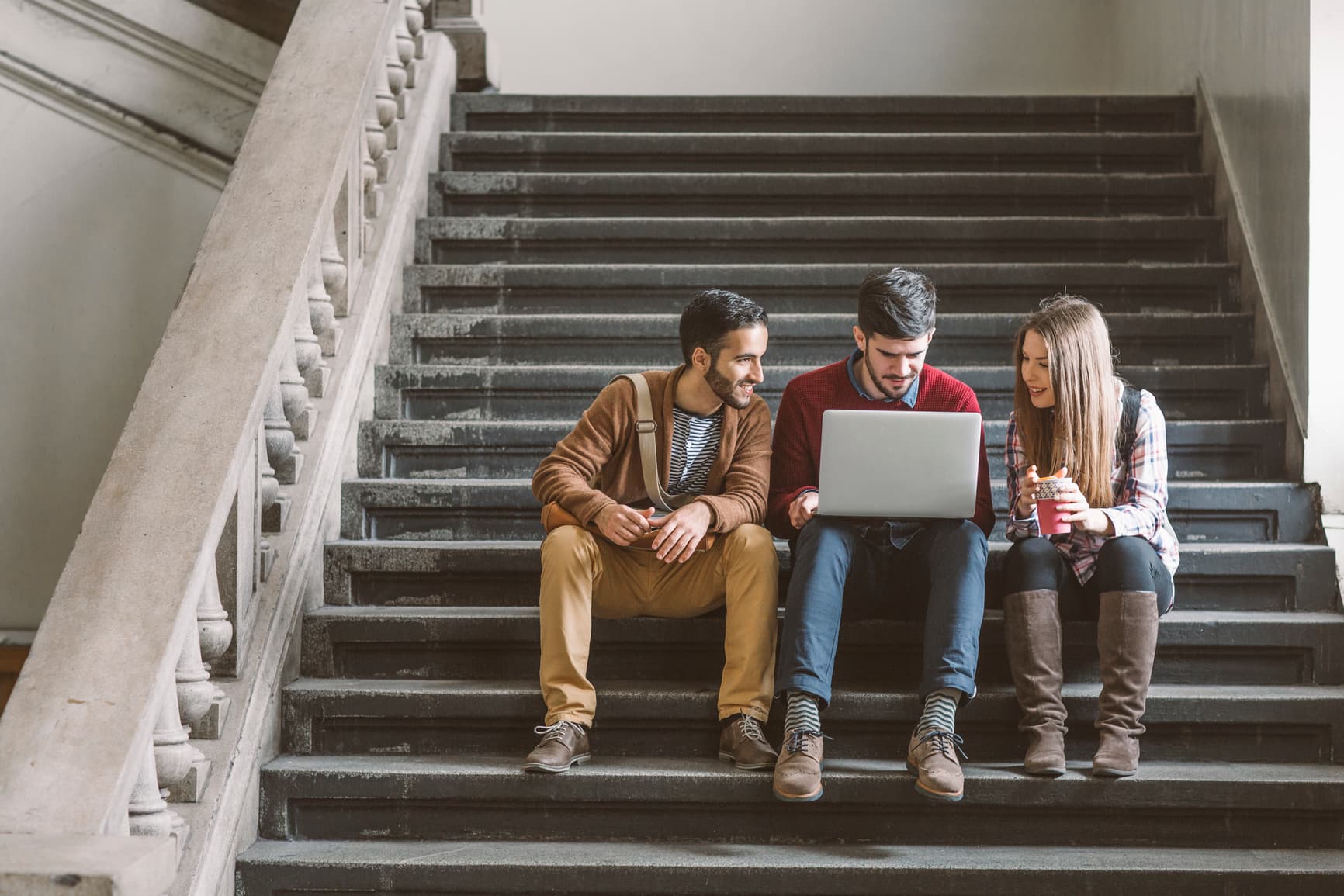 Group-of-college-students-using-a-laptop-in-stairs-should-i-go-to-grad-school