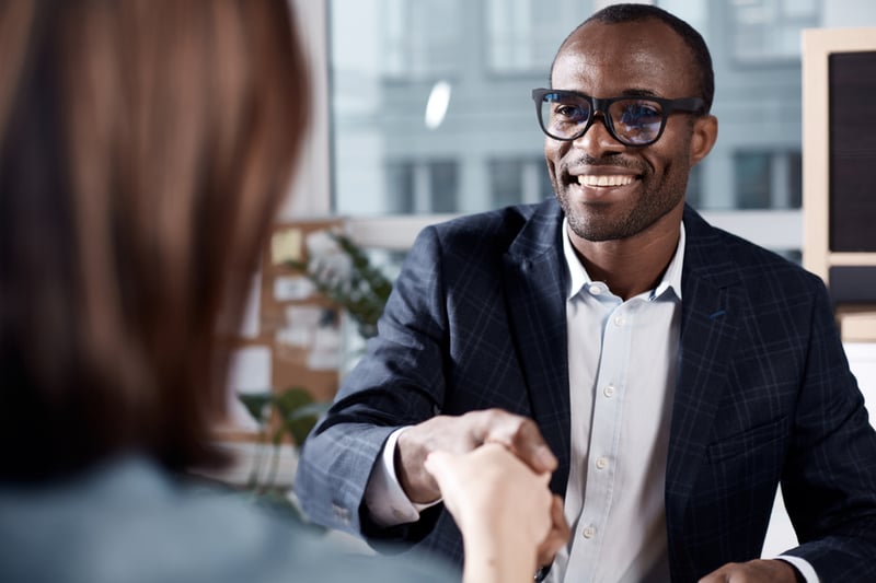 HR-male-interviewer-shaking-womans-hand-action-verbs-for-resume