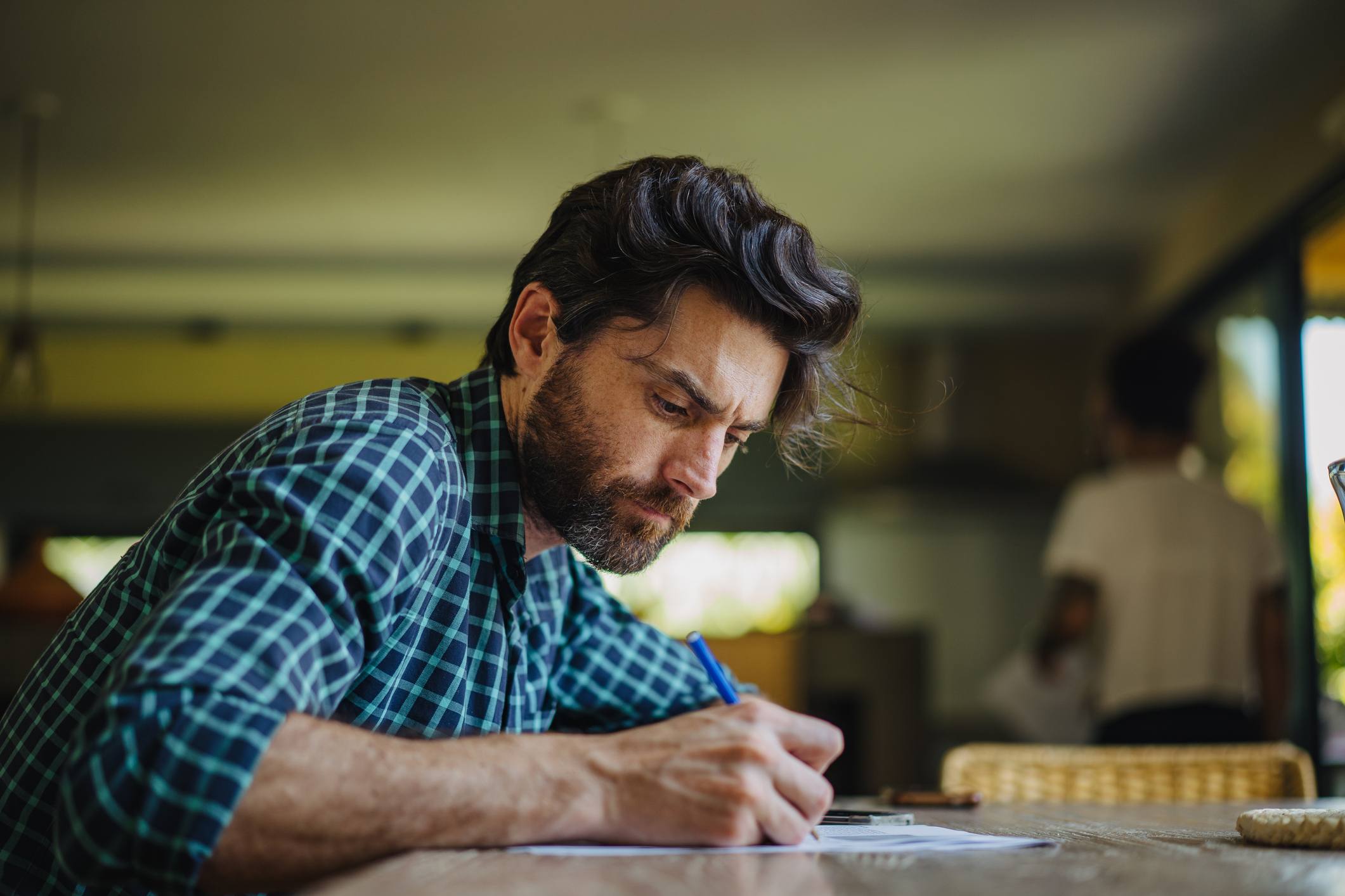 Handsome-Latino-man-is-sitting-at-a-desk-and-writing-career-statement