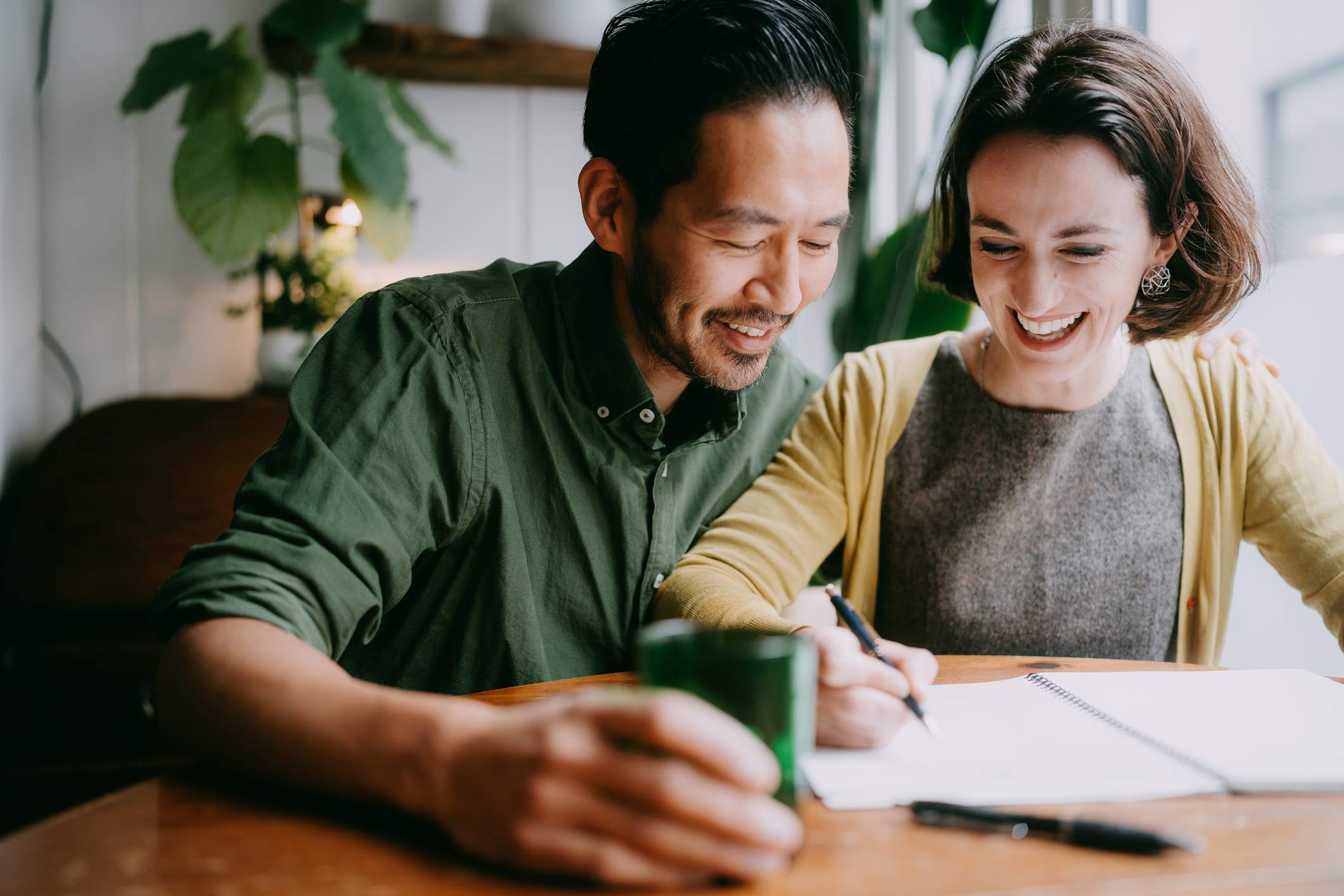 Happy-couple-smiling-writing-in-notebook-at-home-how-to-release-endorphins