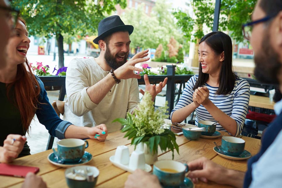 Happy-group-of-friends-talking-and-laughing-at-cafe-being-intentional