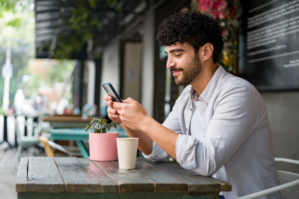 Happy-man-drinking-coffee-and-checking-his-cell-phone-unlimited-pto-pros-and-cons