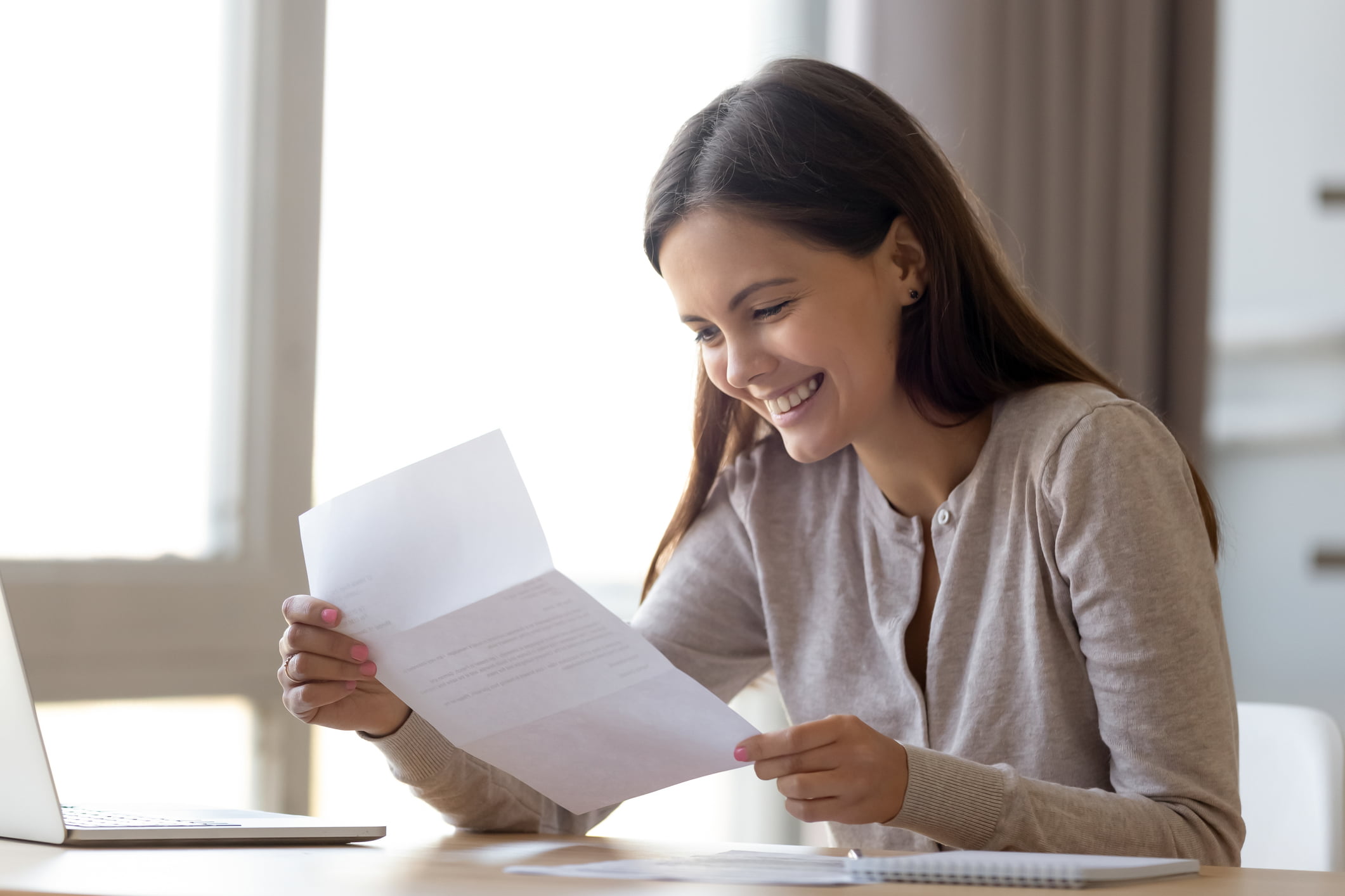 Happy-woman-reading-letter-of-recommendation-laid-off-vs-fired