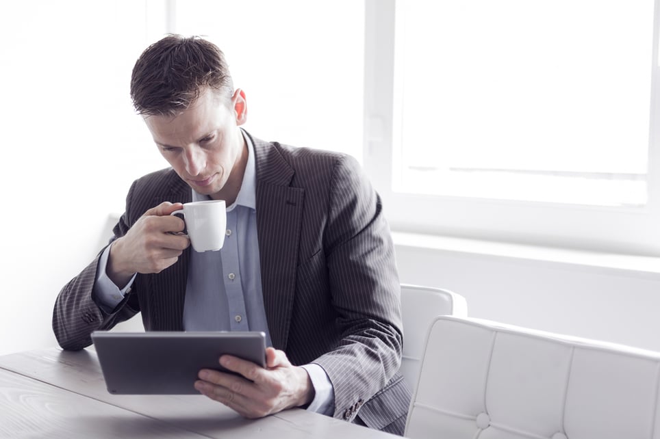 Male-drinking-coffe-using-tablet-wearing-a-suit-linkedin-profile