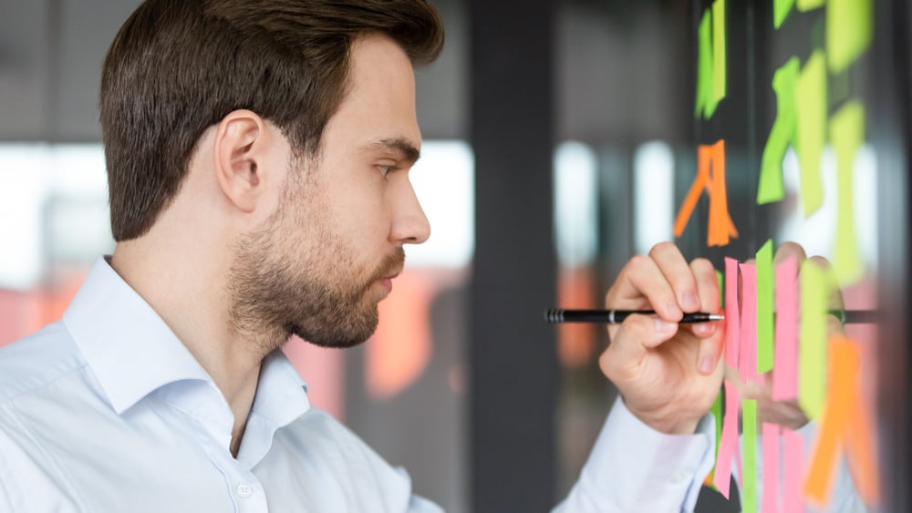 Male-in-front-of-blackboard-writing-how-to-overcome-lack-of-ambition