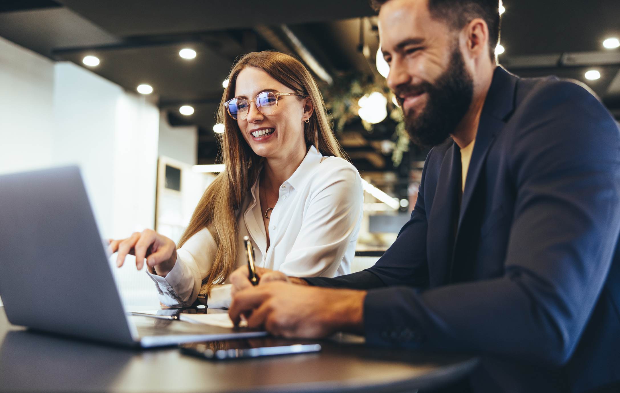 Man-and-woman-at-office-smiling-looking-at-laptop-how-to-end-an-email