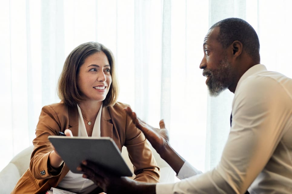 Man-and-woman-smiling-and-looking-at-files-at-meeting-what-makes-a-great-coach