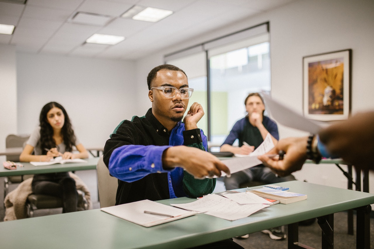 Man-at-college-class-getting-test-back-from-professor-magna-cum-laude-vs-summa-cum-laude