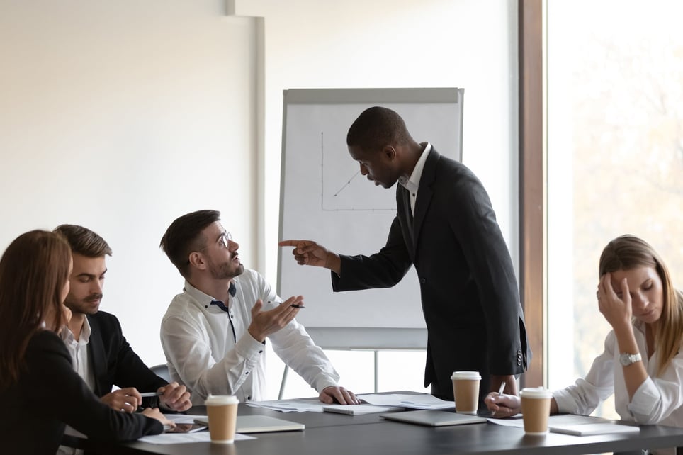 Man-berating-coworker-in-front-of-other-employees-bullying-at-work