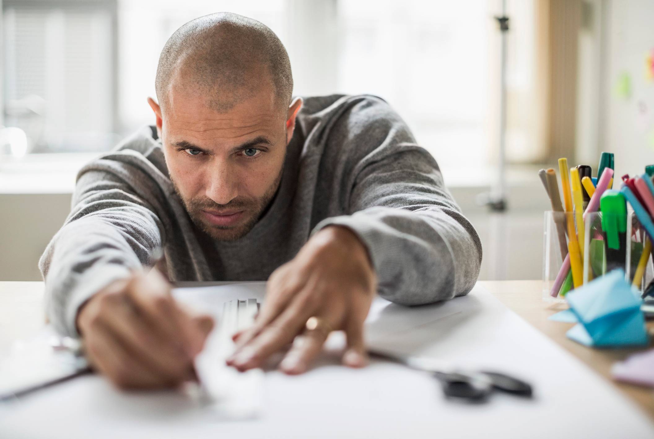 Man-concentrating-while-using-ruler-on-a-project-what-are-the-emotional-triggers-for-empaths