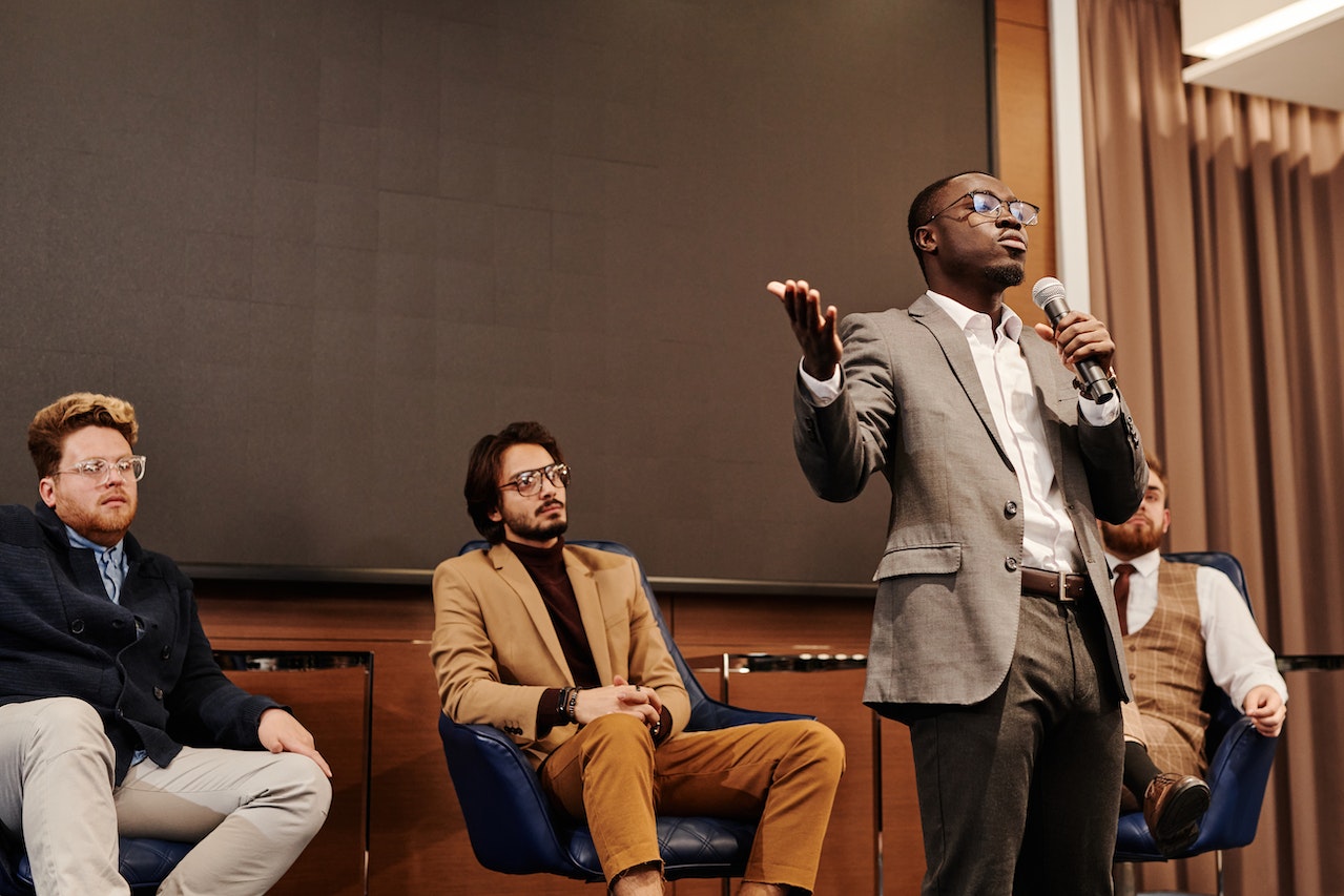 Man-holding-microphone-at-panel-while-talking——how-to-give-a-speech