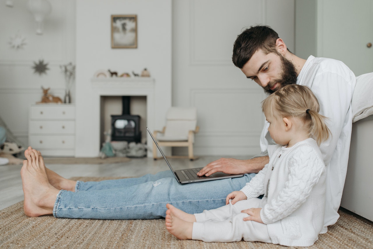 Man-with-toddler-sitting-on-the-floor-using-his-laptop-how-to-put-babysitter-on-a-resume