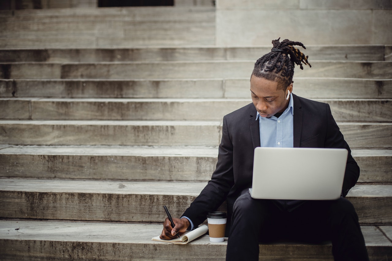 Man-working-outside-on-his-laptop-and-writing-on-laptop-with-earphones-character-references