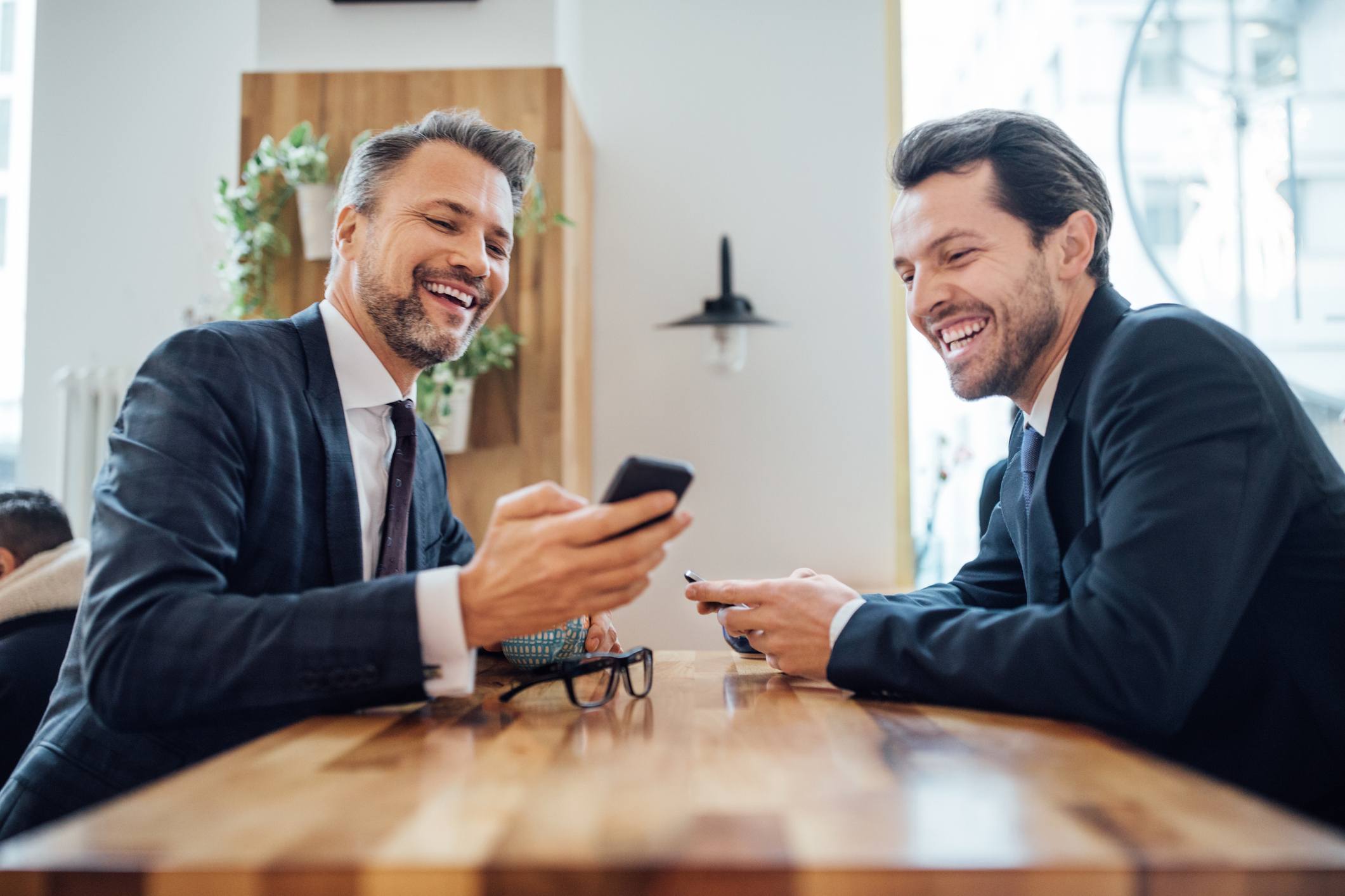 Manager-and-employee-looking-at-something-on-phone-and-laughing-negative-feedback-to-manager-examples