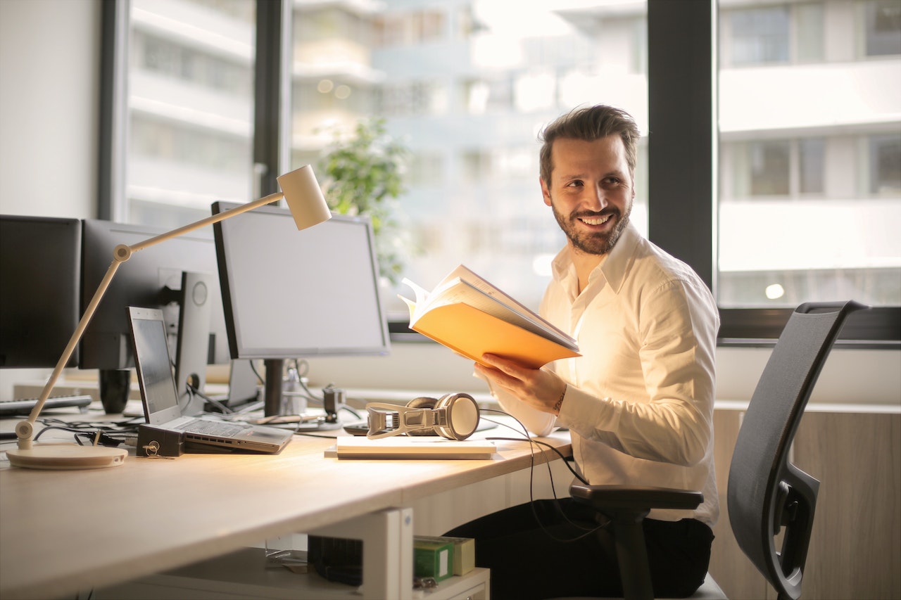 Mat-at-his-desk-smiling-whikle-working-relationship-building-skills-examples