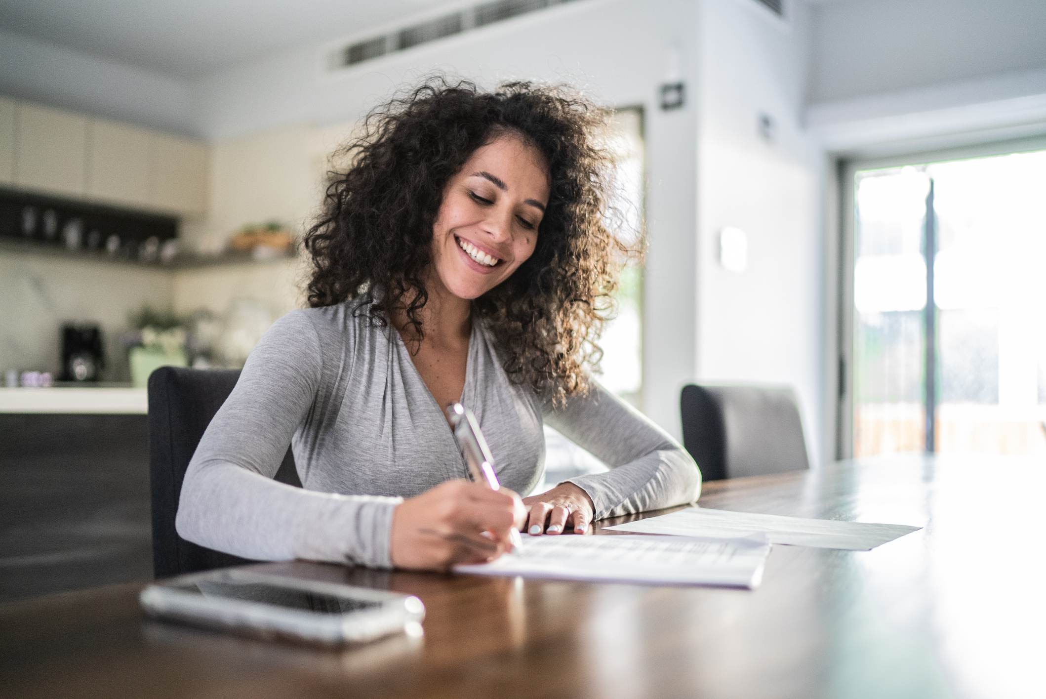 Mid-adult-woman-filling-document-at-home-appreciate-a-team