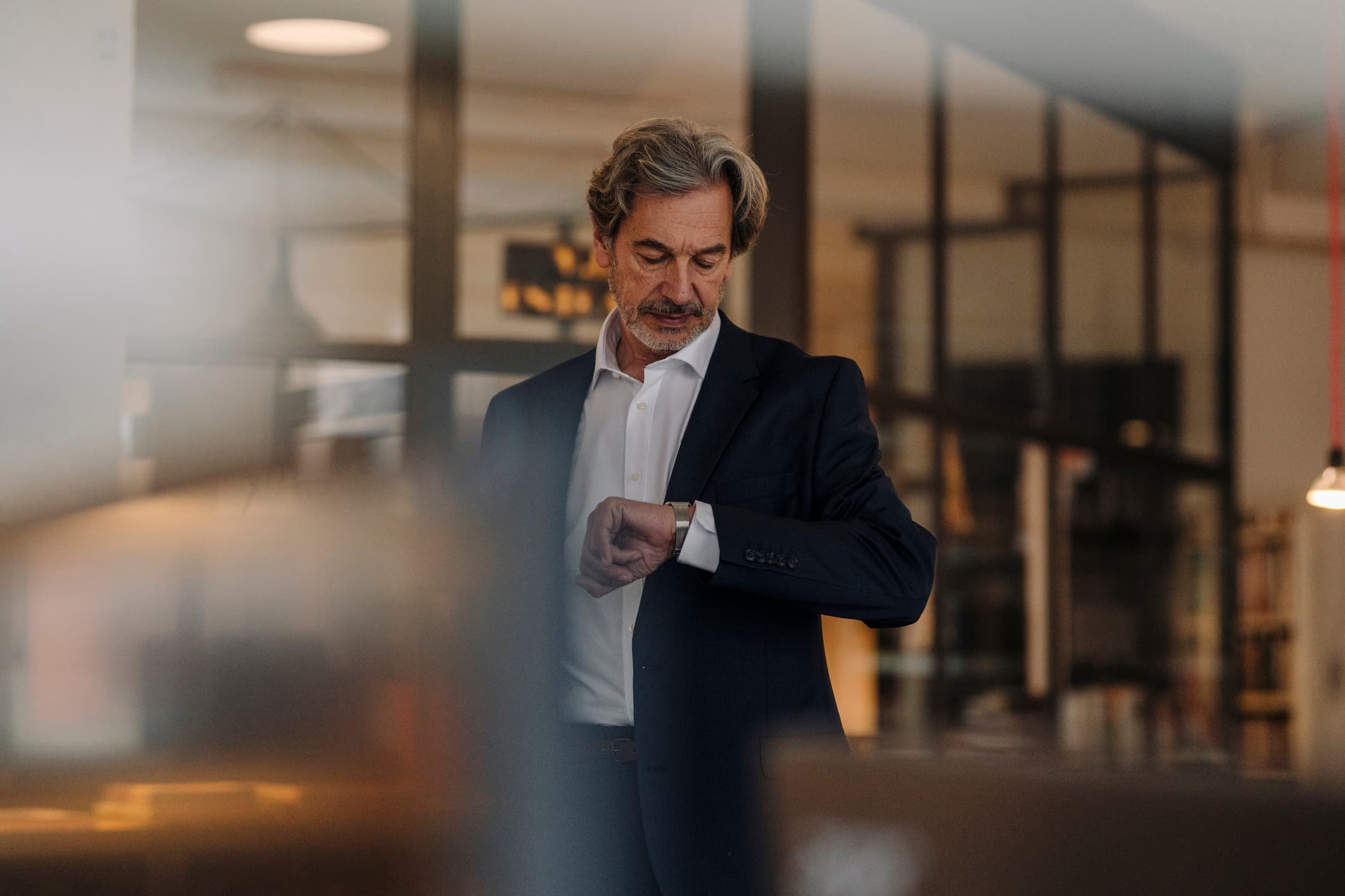 Senior-businessman-checking-the-time-in-the-office-choosing-between-two-jobs