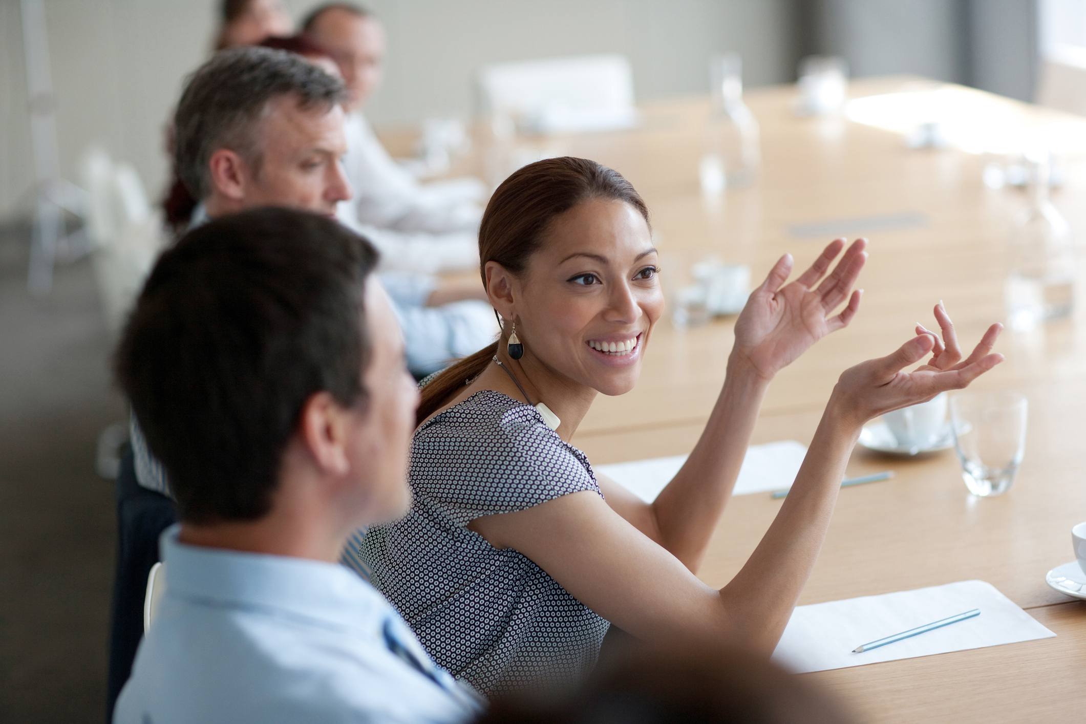 Smiling-businesswoman-gesturing-in-meeting-quotes-to-motivate-a-team