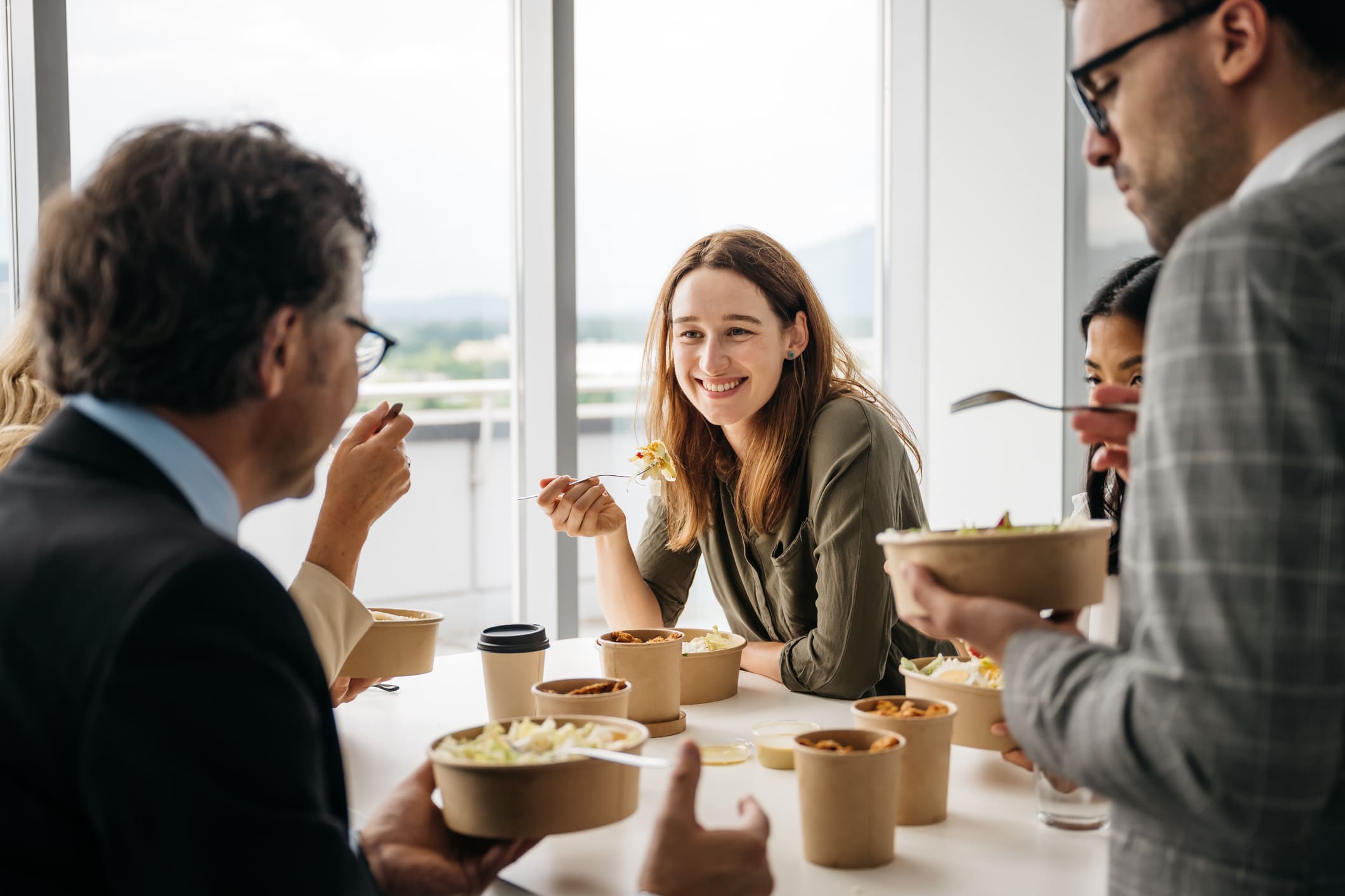 Smiling-woman-enjoying-takeaway-lunch-at-work-how-to-overcome-laziness