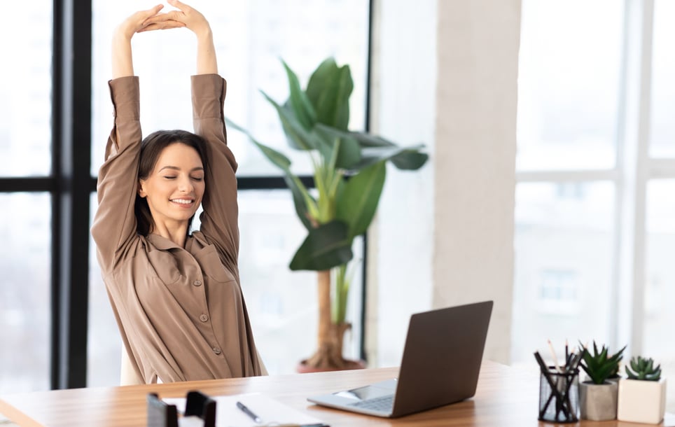 Smiling-woman-relaxing-at-workspace-and-stretching-her-body-how-to-avoid-interruptions-at-work