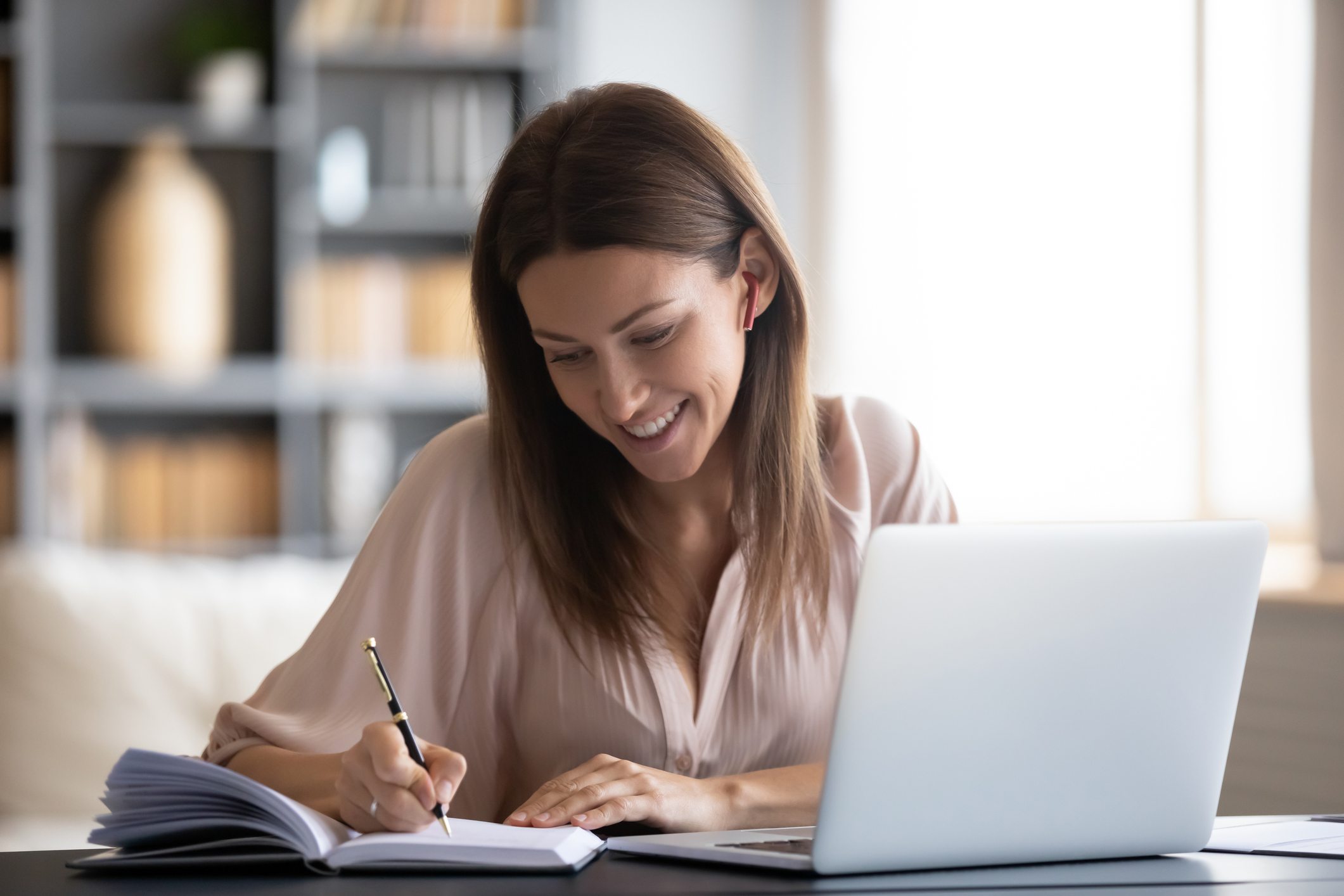 Smiling-woman-writing-in-notebook-how-to-list-references-on-a-resume