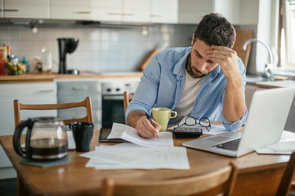 Stressed-man-looking-at-invoices-while-researching-on-computer-current-unemployment-rate