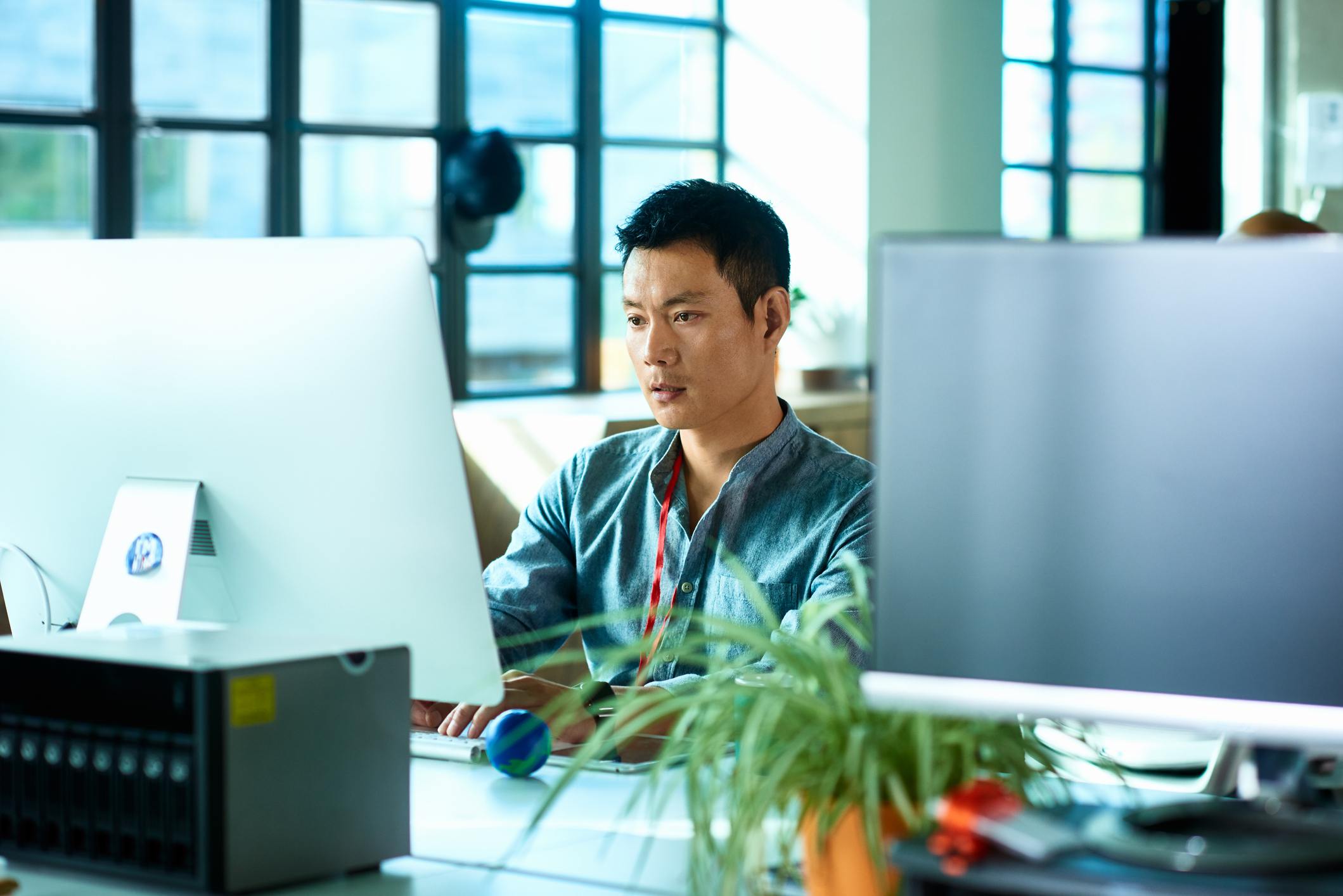 Technology-support-worker-sitting-at-desk-and-looking-at-computer-monitor-characteristics-of-a-determined-person