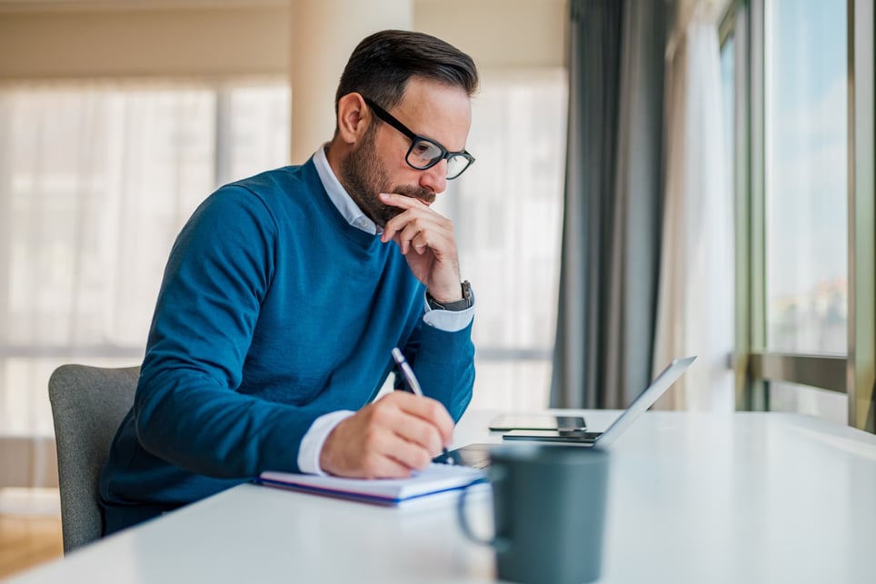 Thoughtful-entrepreneur-working-on-laptop-at-desk-benefits-of-working-for-a-large-company-vs-small-company