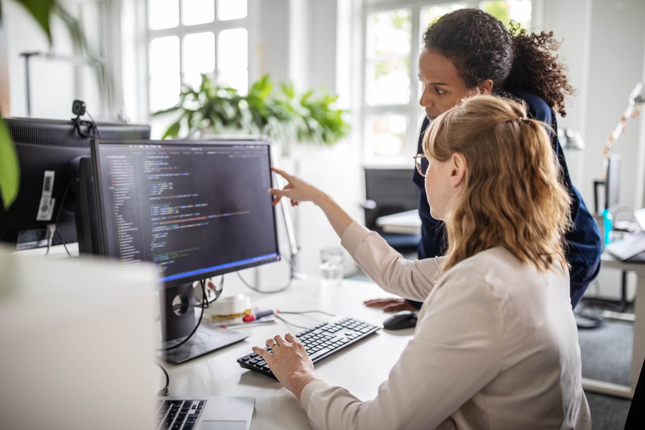 Two-collegues-looking-at-a-code-in-computer-teamwork-skills