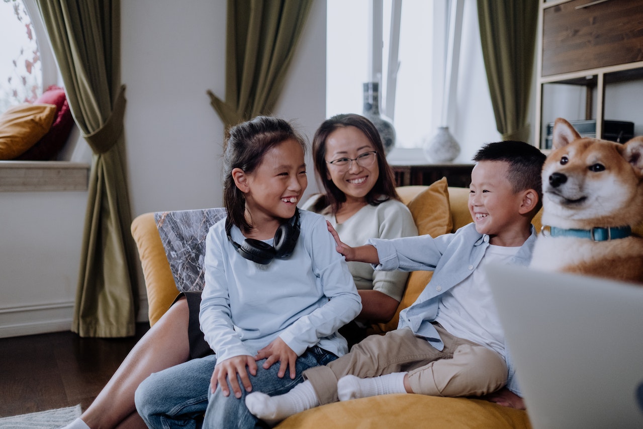 Two-kids-with-dog-and-their-mom-laughing-sitting-on-the-couch-interpersonal-relationships