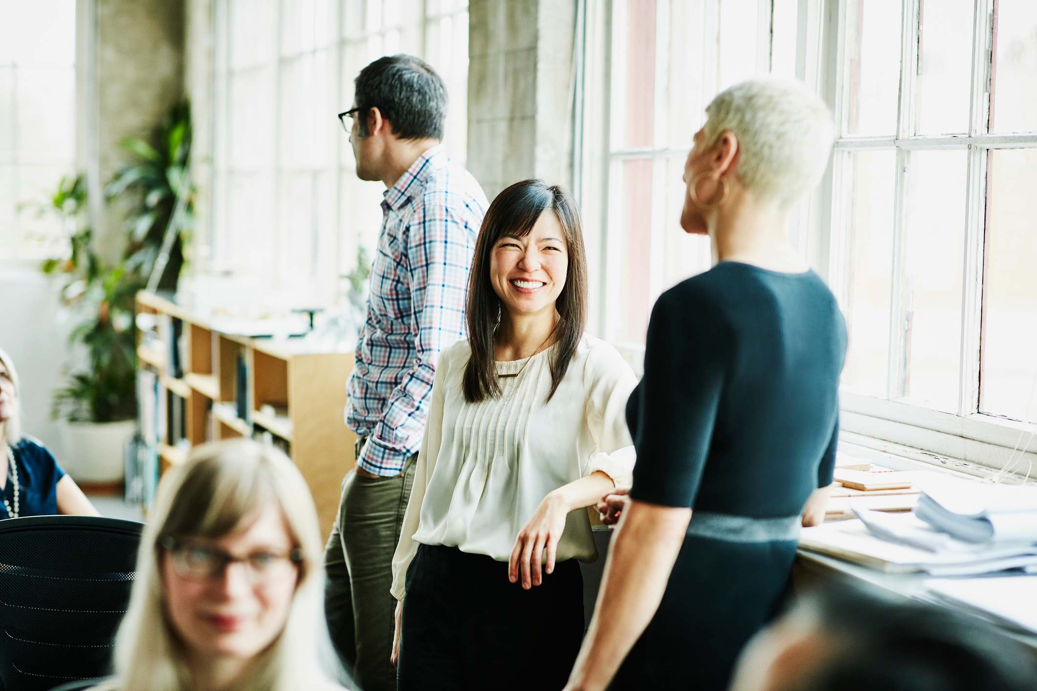 Two-woman-coworkers-smiling-and-talking-to-each-other-team-collaboration