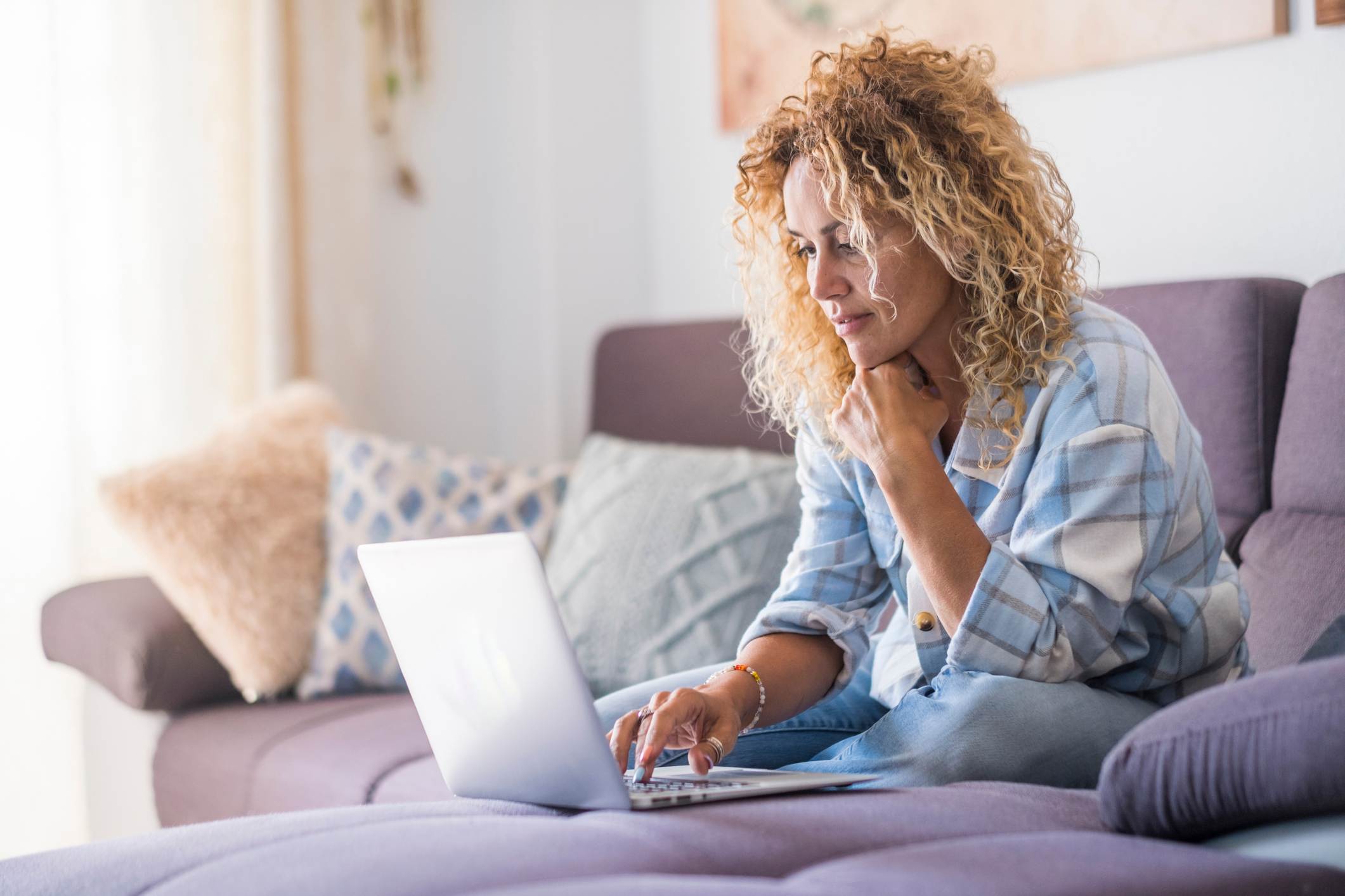 Woman-at-home-sitting-on-couch-looking-for-jobs-in-laptop-part-time-employee-benefits