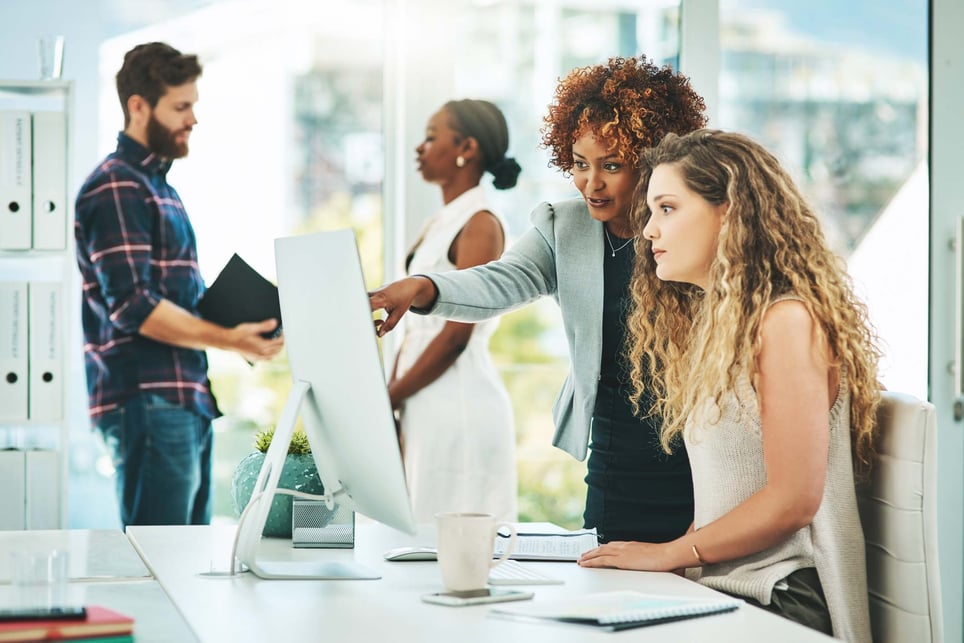 Woman-helping-collegue-find-something-on-computer-first-day-on-the-job