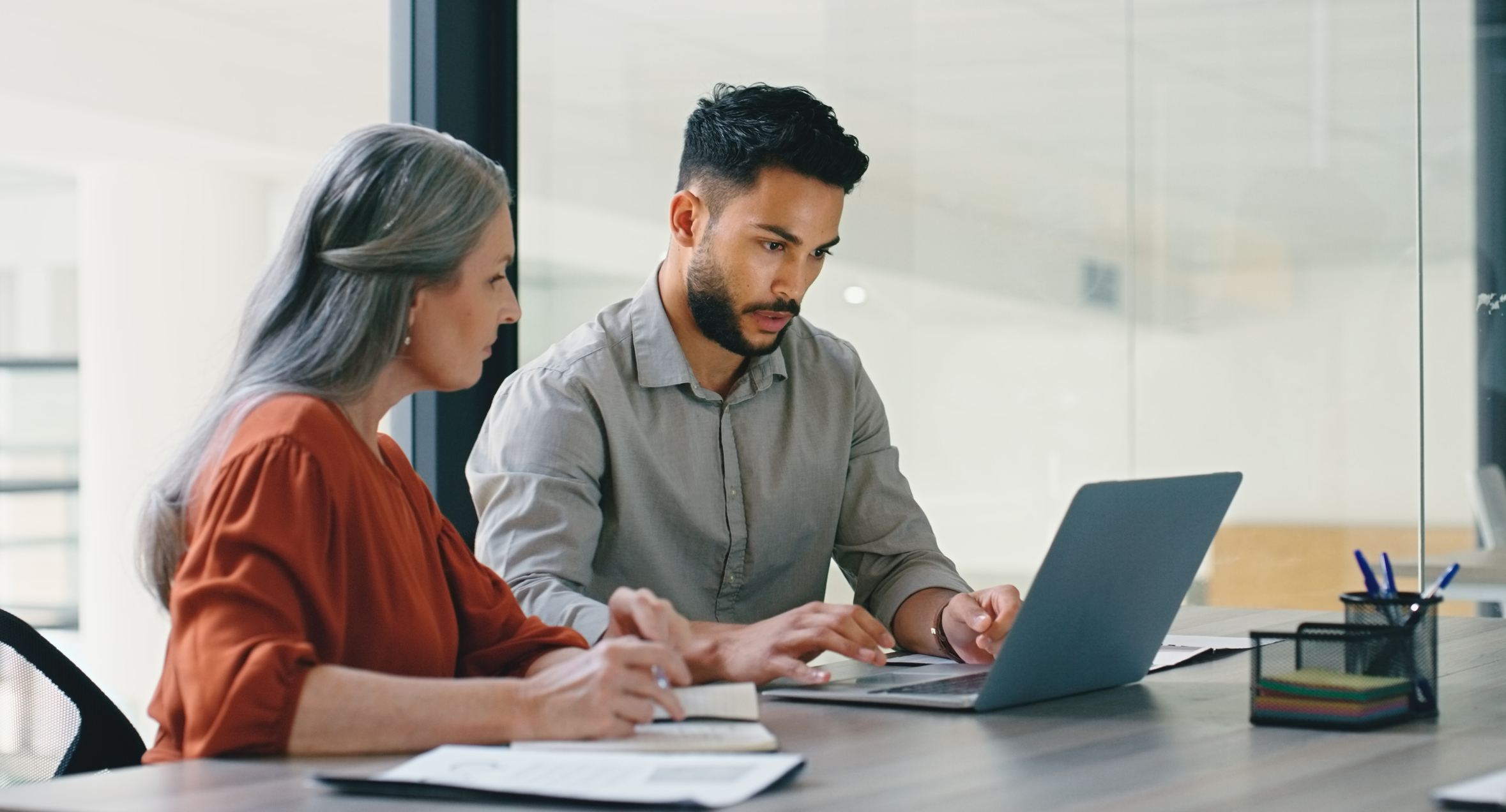 Woman-helping-her-coworker-do-something-in-laptop-how-to-help-someone-with-imposter-syndrome