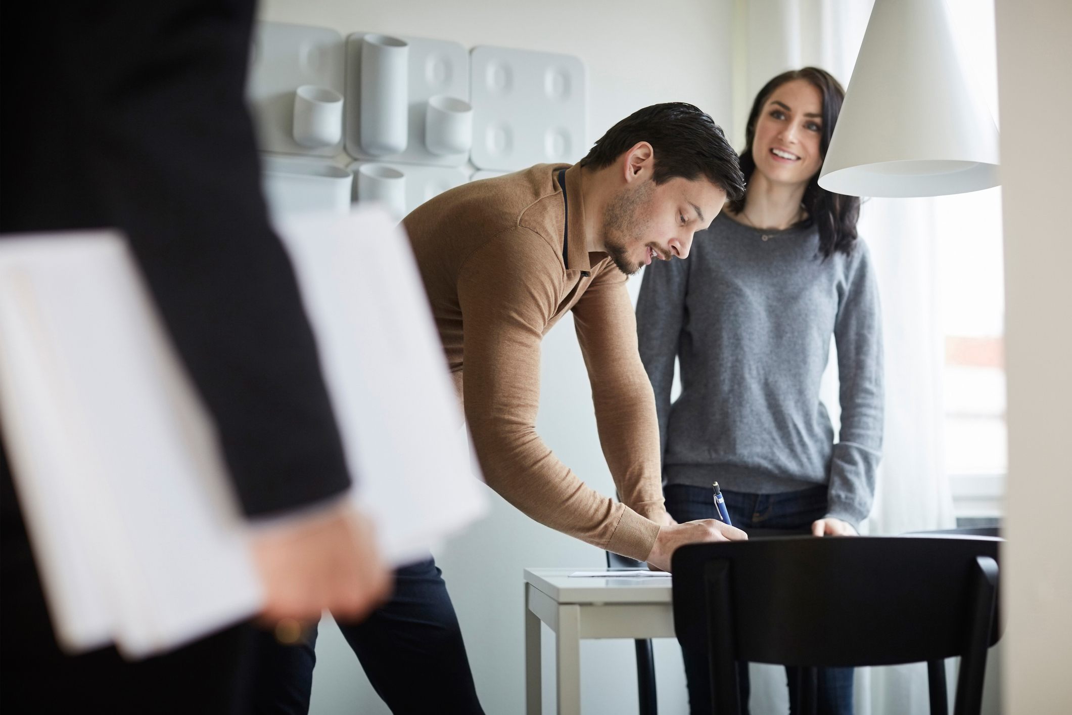 Woman-looking-at-real-estate-agent-while-man-signing-documents-at-new-home-how-to-write-a-professional-email