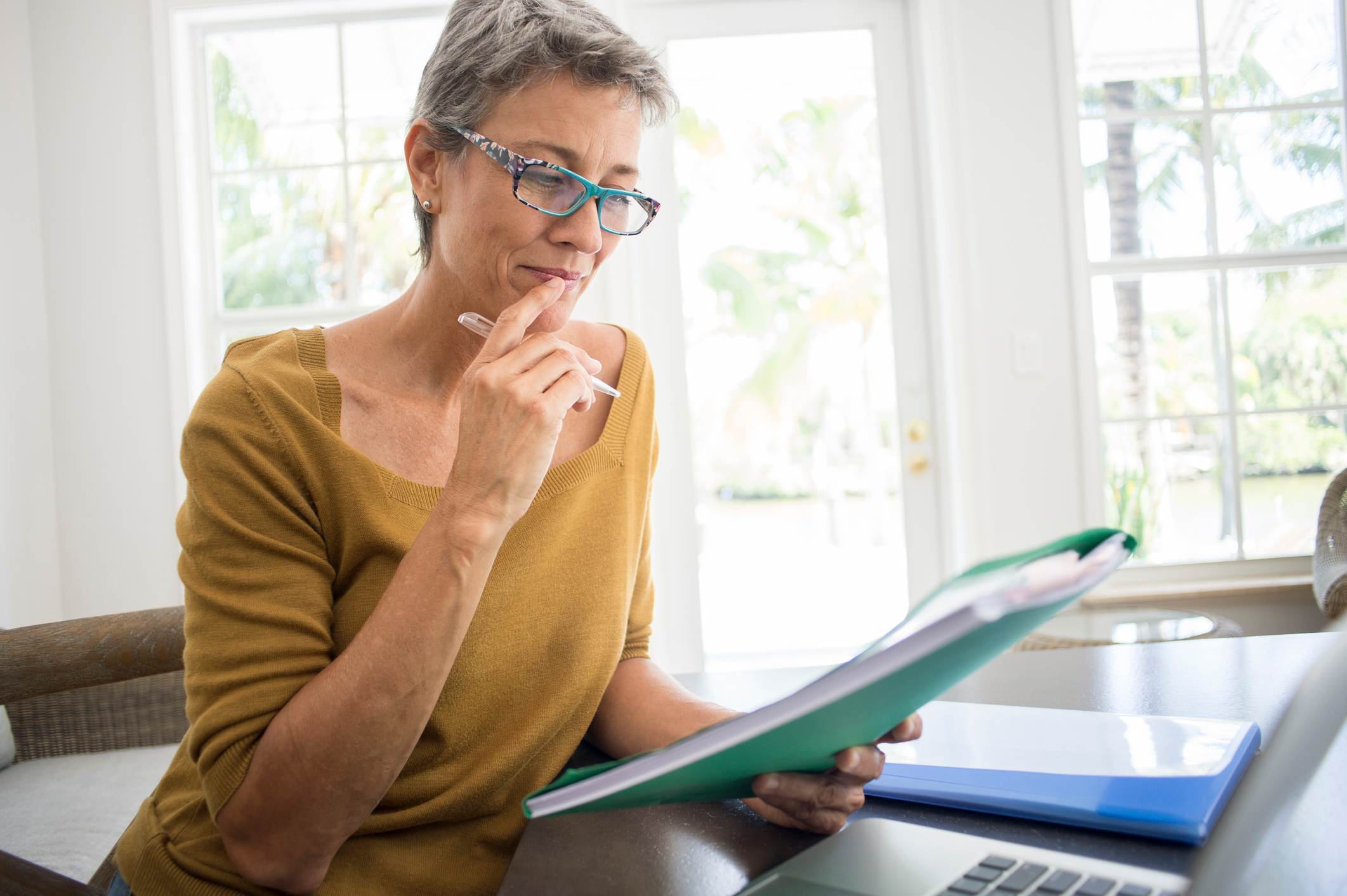 Woman-reading-folder-at-desk-in-living-room-how-to-list-references-on-a-resume