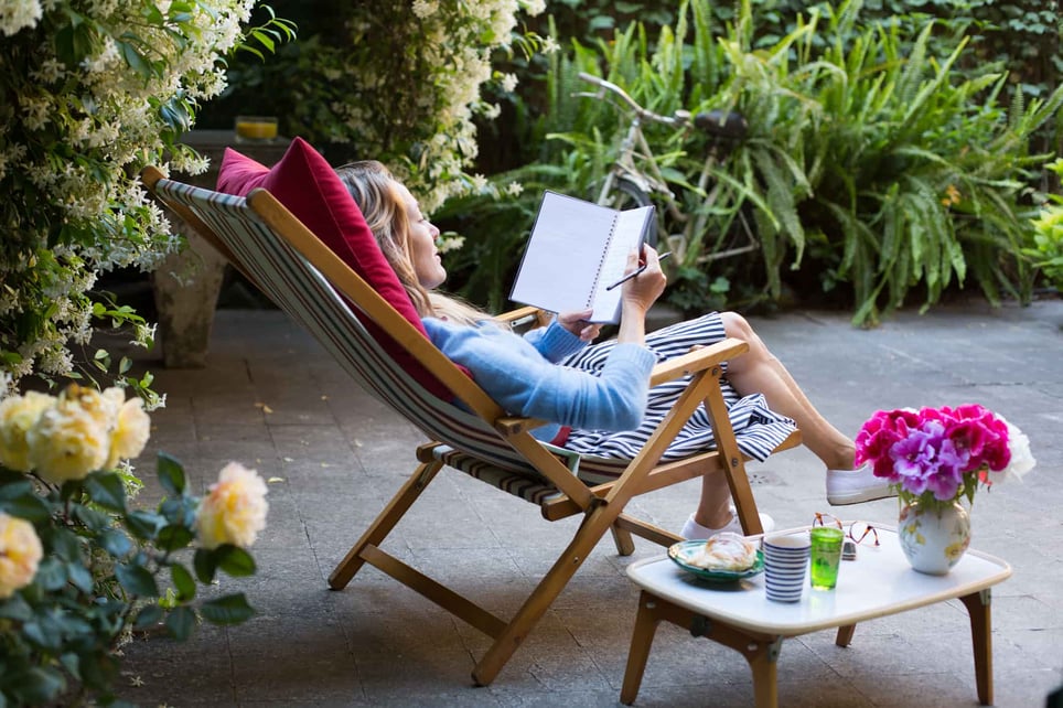 Woman-relaxing-on-deck-chair-in-back-yard-and-writing-in-notebook-things-to-do-with-your-free-time