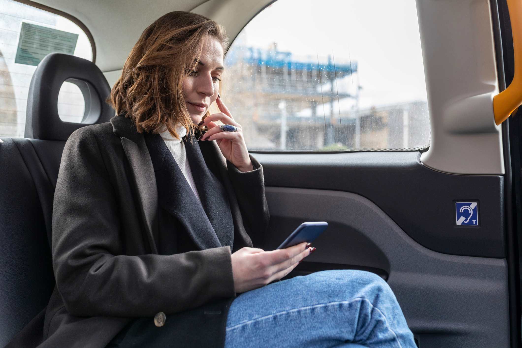 Woman-riding-car-checking-her-phone-taking-a-sabbatical-from-work